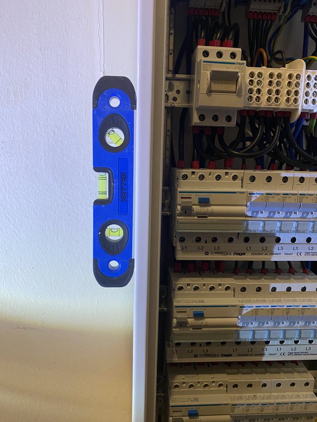 Wasserwaage vor einer Reihe FI-Schutzschalter im Verteilerschrank