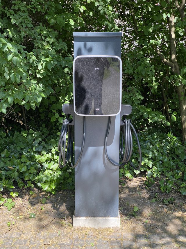 ABL-Wallbox auf einer Standsäule mit aufgehängtem Ladekabel im Außenbereich